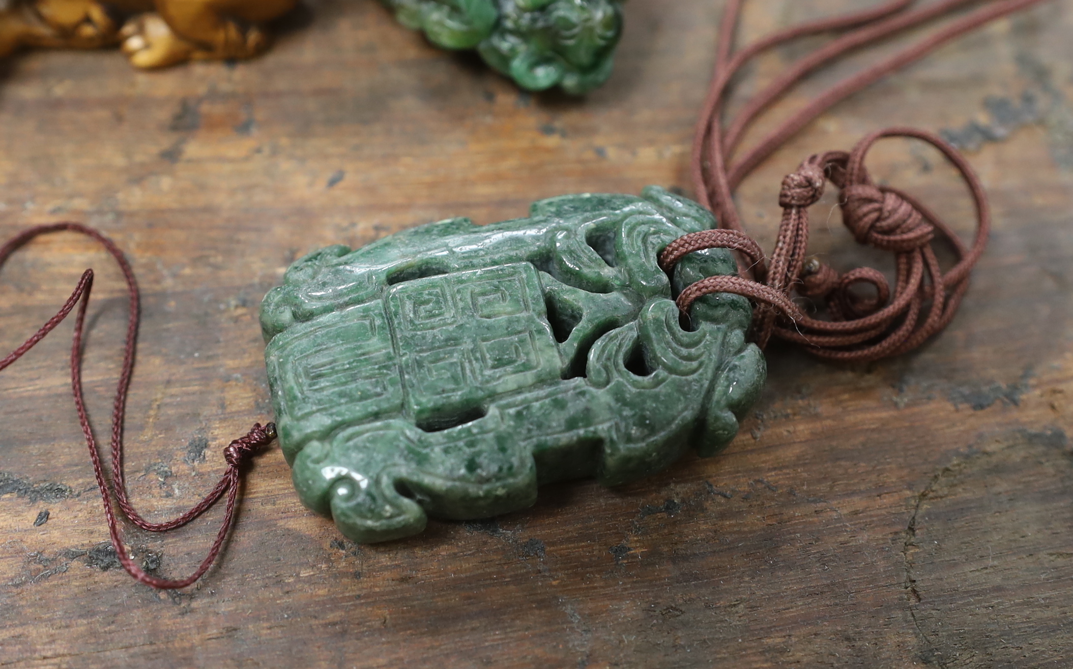 Five Chinese jadeite pendants and two wood lion-dog netsuke, netsuke 3.5 high